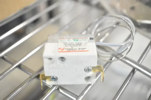 Hobart 00-479348 Sharpener Assy on metal rack, brand new condition, white casing, visible label with part details.
