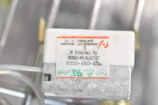 Close-up of a label on a device showing markings and numbers. The label includes serial and model numbers.