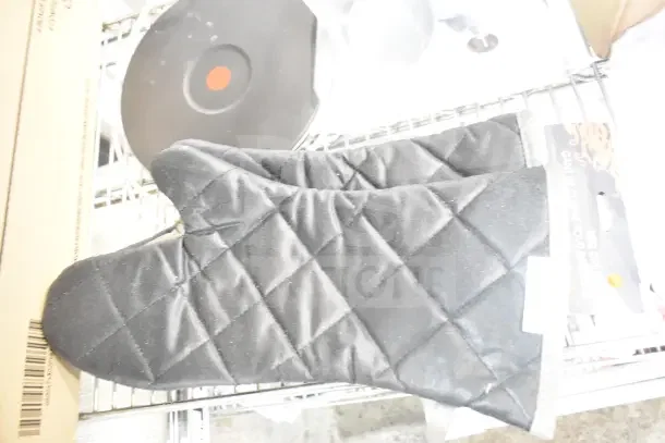 Black quilted oven mitt on shelf, featuring flame retardant material by Outset®. New condition.