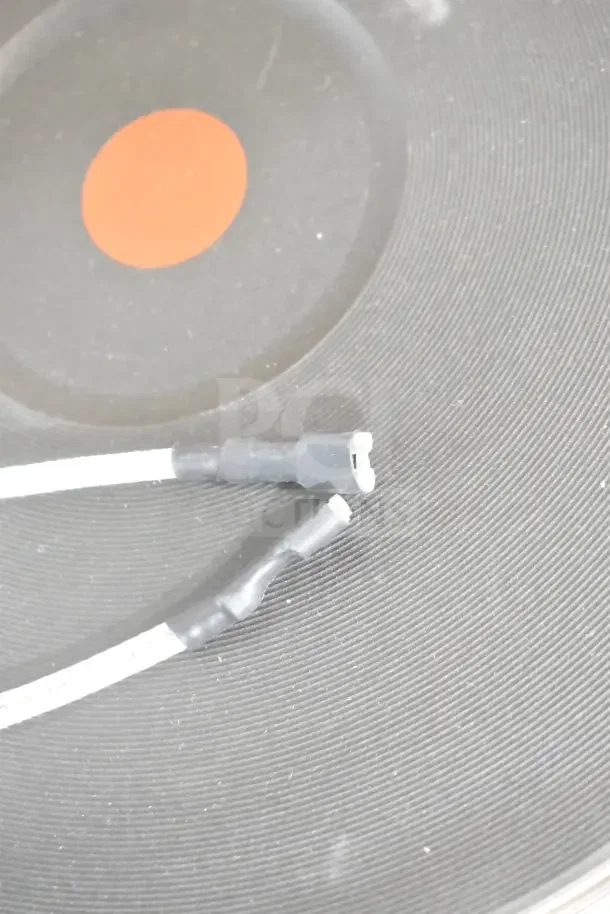 Close-up of wiring connectors on a scratched black surface, possibly part of commercial kitchen equipment.