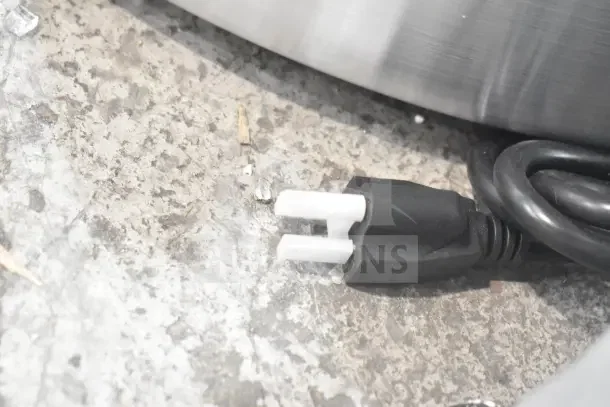 Black power plug of a Backyard Pro 554SL112E meat slicer on a concrete floor.