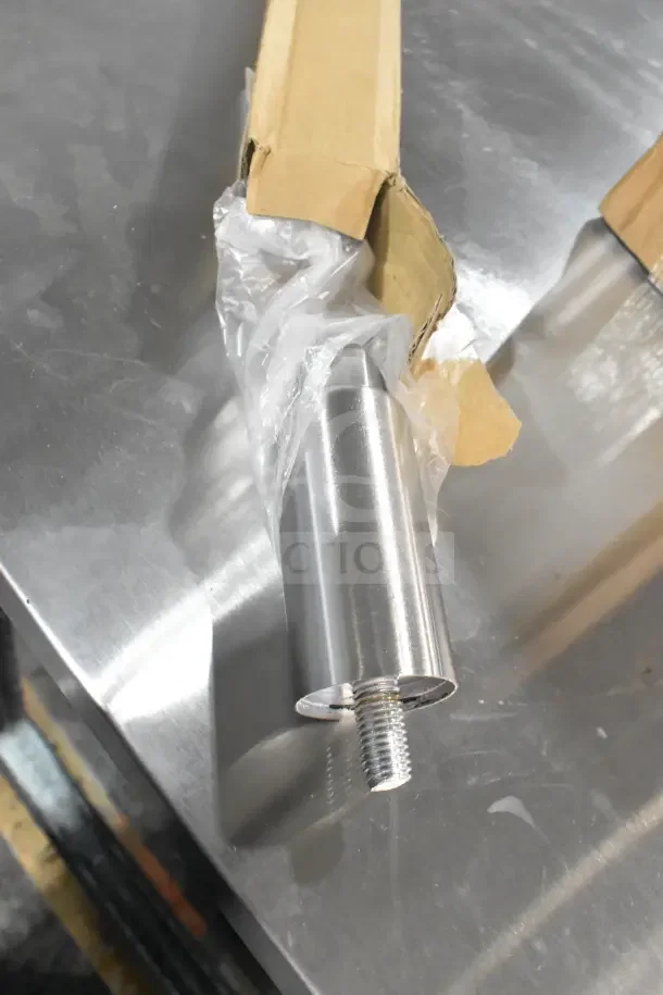 Brand new Delfield metal leg, partially wrapped in plastic, showing a threaded end.
