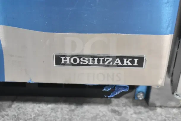 Hoshizaki AM-50BAK ice machine label; stainless steel surface with visible protective film and Hoshizaki branding.