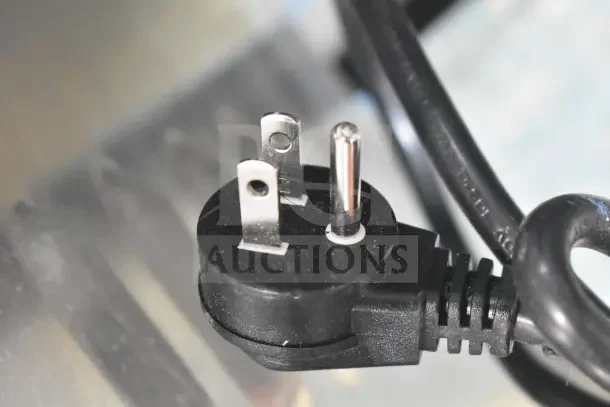 Close-up view of a three-prong plug attached to the Hoshizaki AM-50BAK ice machine, showing power compatibility.