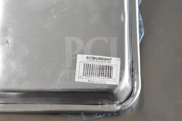 18 new scratch and dent aluminum baking pans, including 407BUNEGHT eighth size, 19 gauge wire in rim, label visible.