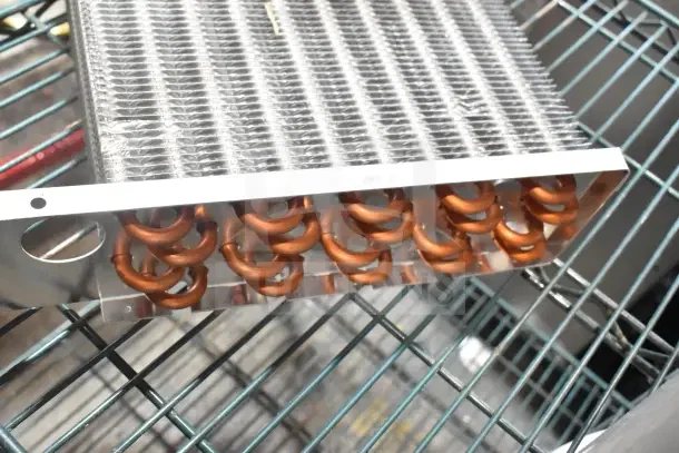 Brand new evaporator coil with slight scratches and dents, featuring copper tubing and aluminum fins.