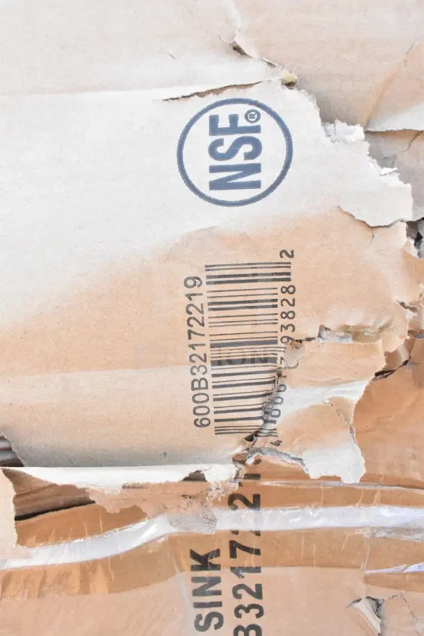 Cardboard box with "NSF" logo and barcode, labeled "sink," showing damage. Part of a 3-item scratch and dent auction.
