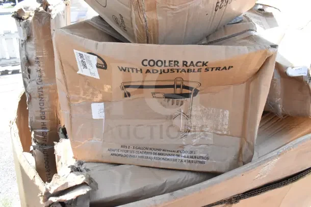 Cardboard boxes containing scratch and dent items, including a cooler rack with adjustable strap. Boxes show signs of damage.