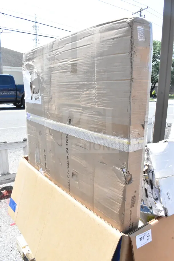 Cardboard boxes containing scratch and dent items, including Ashland grease trap and chafers. Boxes show wear and tear.