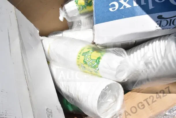 Boxes and wrapped stacks of disposable cups with lemon print, assorted scratch and dent items visible.