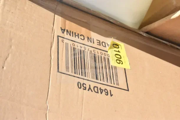 Cardboard box with barcode and "Made in China" label, auction tag number 0106, containing assorted scratch and dent items.