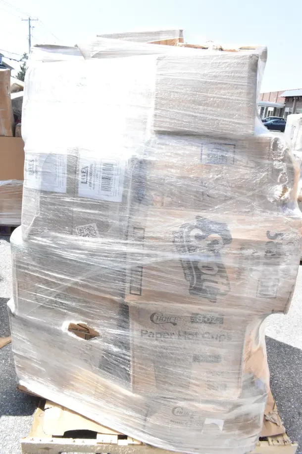 Pallet wrapped in plastic with multiple boxes labeled "Choice" and "Scott," containing new scratch and dent hot and cold cups, plates, and portion cups.