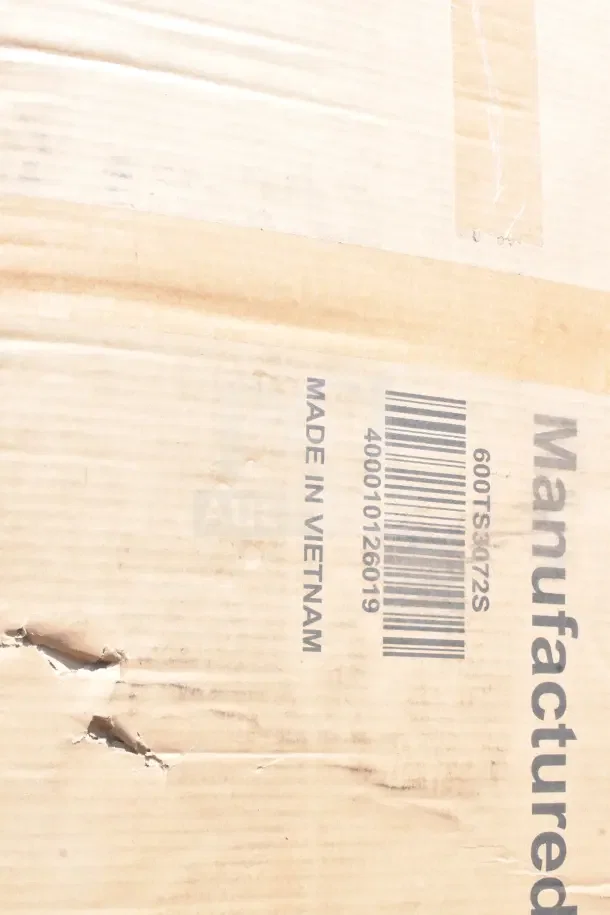 Cardboard box with scratches and barcode, marked "Made in Vietnam." Contains new scratch and dent items like shelves and racks.