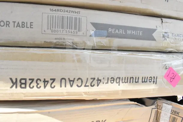 Cardboard boxes labeled "164RD242WHT" and "Pearl White," containing brand new scratch and dent tables. Made in China.