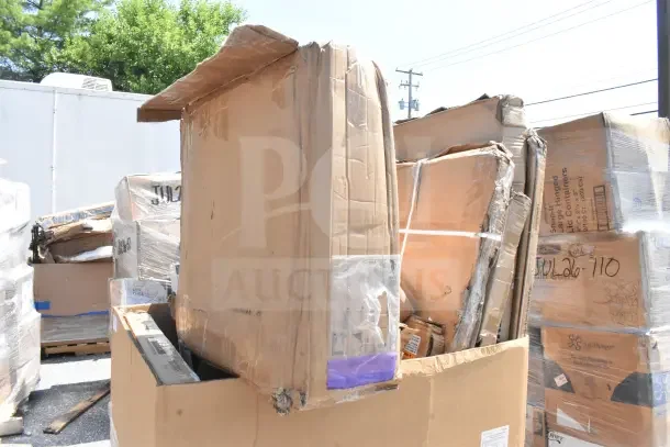 Multiple cardboard boxes containing scratch and dent items, including a tabletop, sheet pan rack, and high chair. Boxes show signs of wear.