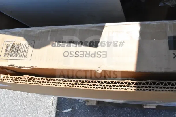 Cardboard box labeled "ESPRESSO #3493030BESP" indicating scratch and dent items including tabletop, sheet pan rack, high chair.