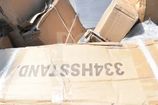 Boxes of scratch and dent items, including a tabletop, sheet pan rack, and high chair. Visible packaging damage.