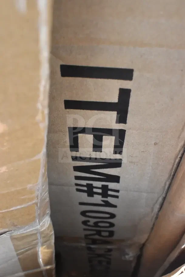 Cardboard box labeled "ITEM#109RACKETS," containing scratch and dent items like a tabletop, sheet pan rack, and high chair.