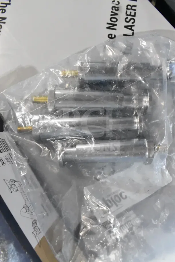 Plastic bag containing metal assembly components with brass screws, lies atop a manual with schematics and text.