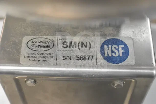 Two Yamato Accu-Weigh SM(N) Universal Dial Scales on a stand. Model tag shows "SM(N)" and NSF logo. Serial number 56877.