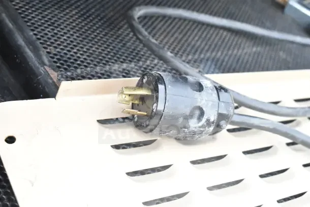 Killion Merchandiser power plug, black, three-pronged, on metal vented surface; suitable for 120/208-240 volts use.