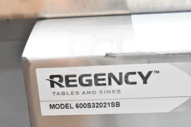 "Regency 600S32021SB label on a commercial utility sink, featuring stainless steel finish with minor scratches and dents."