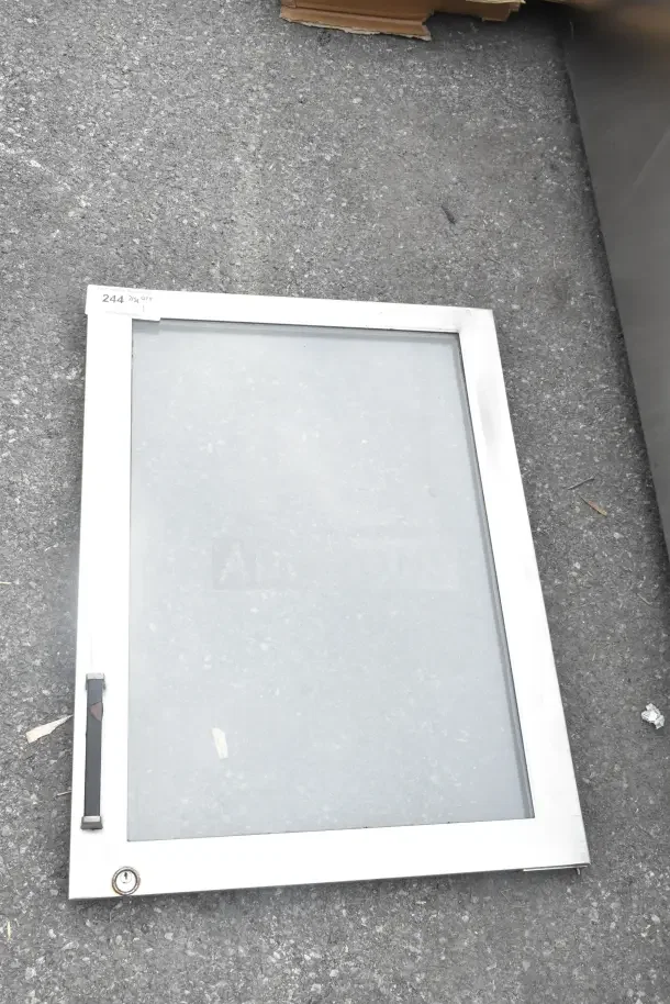 Brand new replacement door with metal frame, scratch and dent condition, shown on asphalt. Label reads "244 7x3."