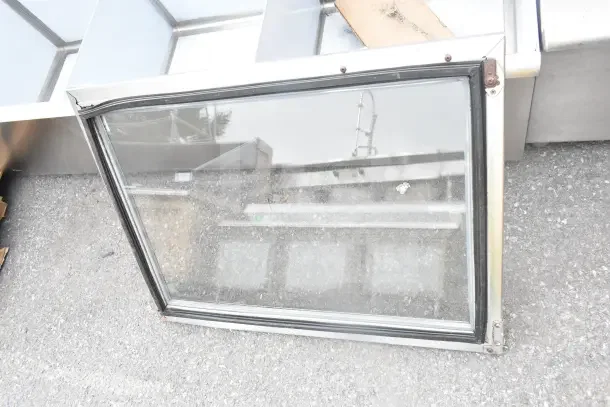 Brand new replacement door, scratch and dent condition. Glass pane, metal frame, visible corner dents. Auction item.