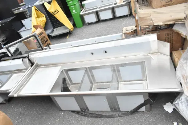 Brand new Regency 600DDTS384LFT dish table with 3 compartments, 16-gauge, 7' length, no legs, left drainboard, visible scratches.