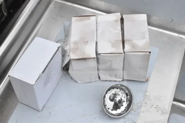Boxes on Steelton commercial sink with drainboard; new with visible dent; includes chrome strainer.