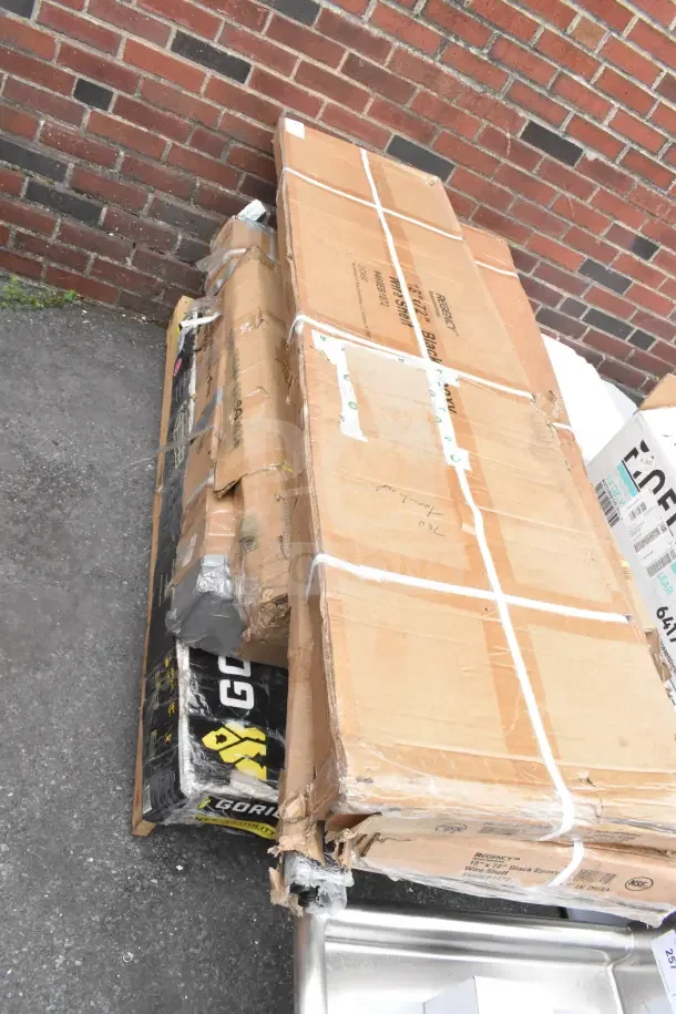 Boxes of scratch and dent items including a utility cart and equipment stand, sealed with packing tape, showing slight damage.