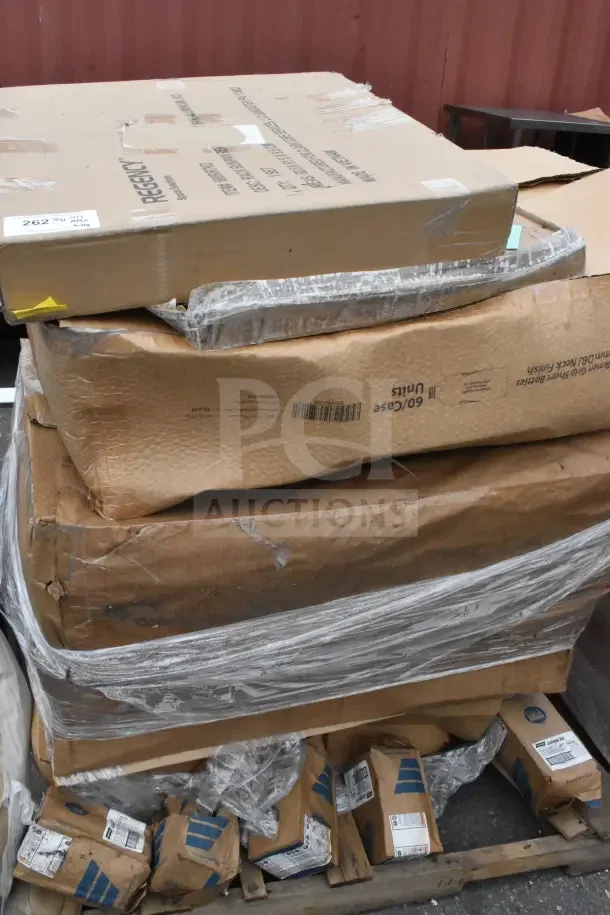 Stack of 11 brand new scratch and dent items including a pan rack and bottles, in original packaging. Regency brand visible.
