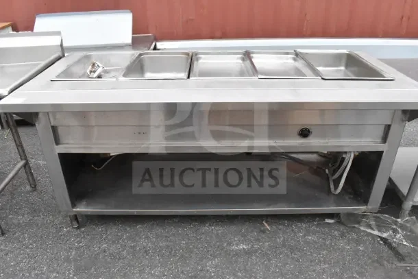 Stainless steel steam table with under shelf, features three compartments and control knob, showing signs of wear.