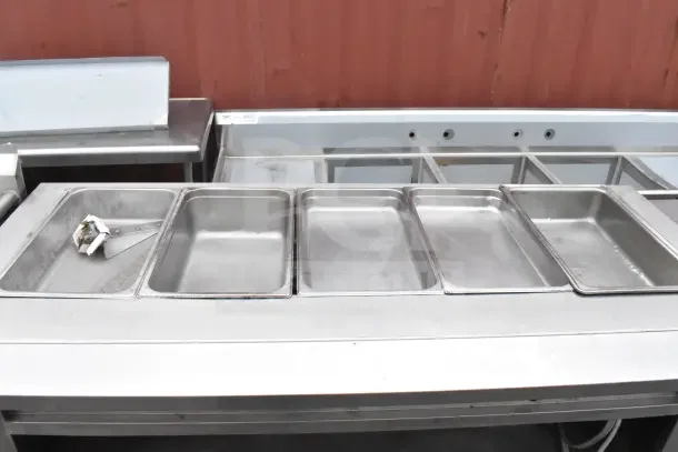 Metal steam table with under shelf, five compartments, stainless steel, used condition, suitable for catering or buffet use.