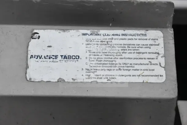 Advance Tabco label on commercial 3 bay sink with dual drain boards, showing cleaning instructions and NSF certification.