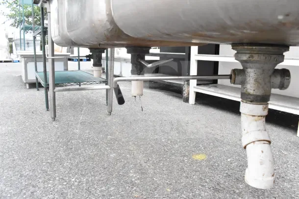 Advance Tabco commercial 3 bay sink with dual drain boards, stainless steel, visible under plumbing, used condition.