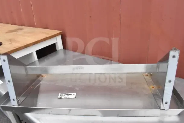 Metal wall mount shelf with visible rust spots, labeled "Caution: Avoid Sharp Edges," in fair condition.