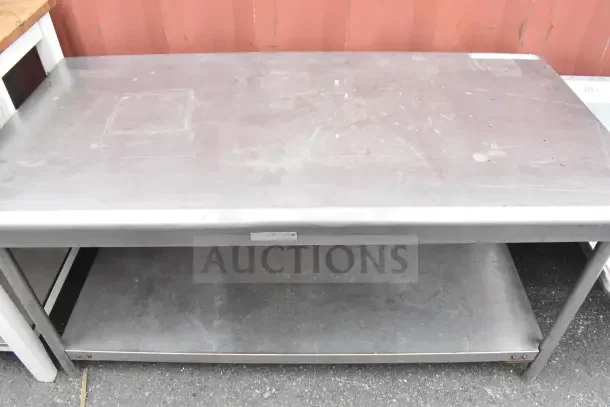 Steel table with under shelf, used condition, visible surface wear. Ideal for industrial or kitchen use.
