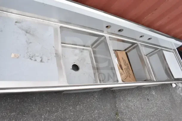 "Brand new Regency 600S32323224 121-inch commercial sink, three compartments, galvanized steel legs, two 24-inch drainboards, visible scratches."