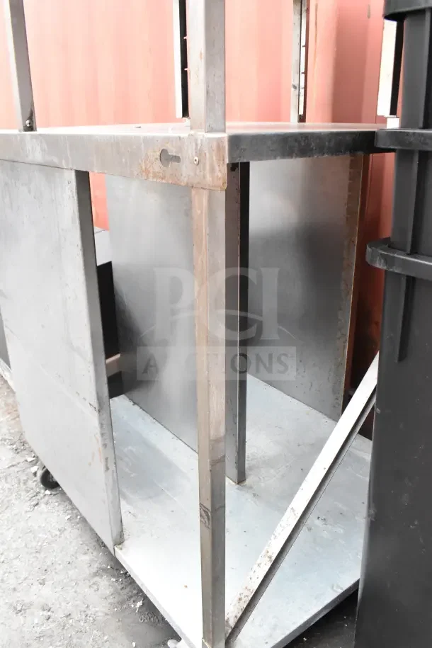 Cart with over shelf on commercial casters, metal construction, used condition with visible rust, ideal for storage.