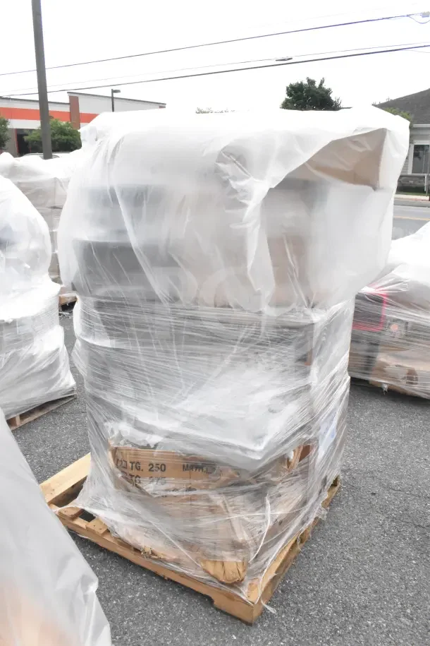 Plastic-wrapped pallet containing 13 brand new scratch and dent items, including dough sheeter and food pans, on an outdoor surface.