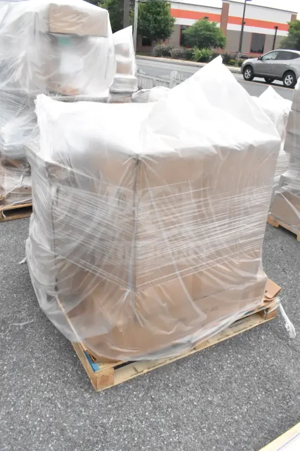 Plastic-wrapped pallet of seven brand new scratch and dent items, including a sink and filler table, ready for auction.