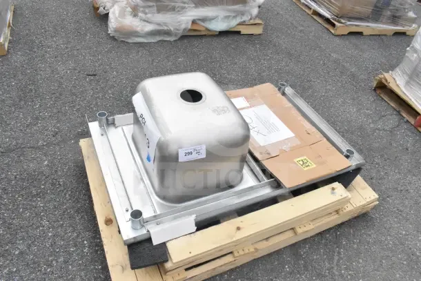 Brand new counter with sink bay, scratch and dent condition, stainless steel, stacked on a pallet with packaging labels visible.