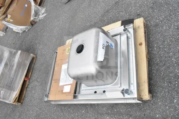Brand new counter with sink bay on a pallet, showing slight scratches and dents, metal finish, labeled "PCL 3."