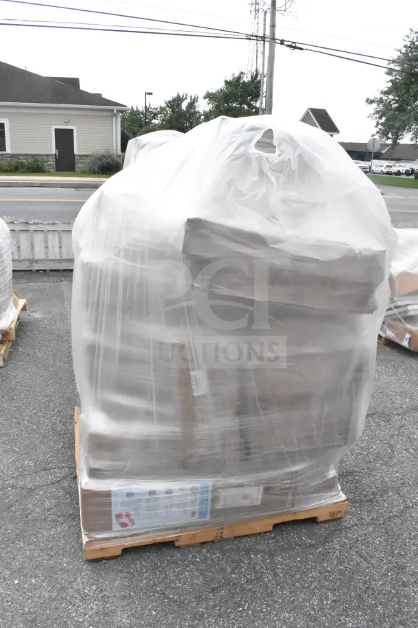 Shrink-wrapped pallet of 21 brand new scratch and dent items, including grinder plates and wine glasses, on asphalt surface.