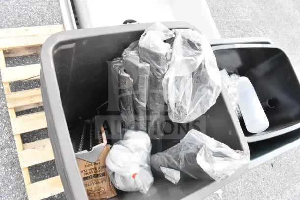 Brand new scratch and dent items including trash cans and a sink, in packaging, visible wear, on a pallet.