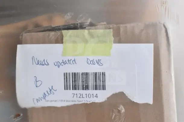 Label on a box with handwritten note saying "Needs updated basics." Barcode and text "San Jamar L1014 Stainless Steel" visible.