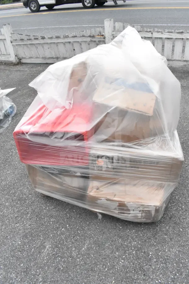 Shrink-wrapped pallet with 11 brand new but scratch and dent items, including a red work table, plates, and mop bucket.