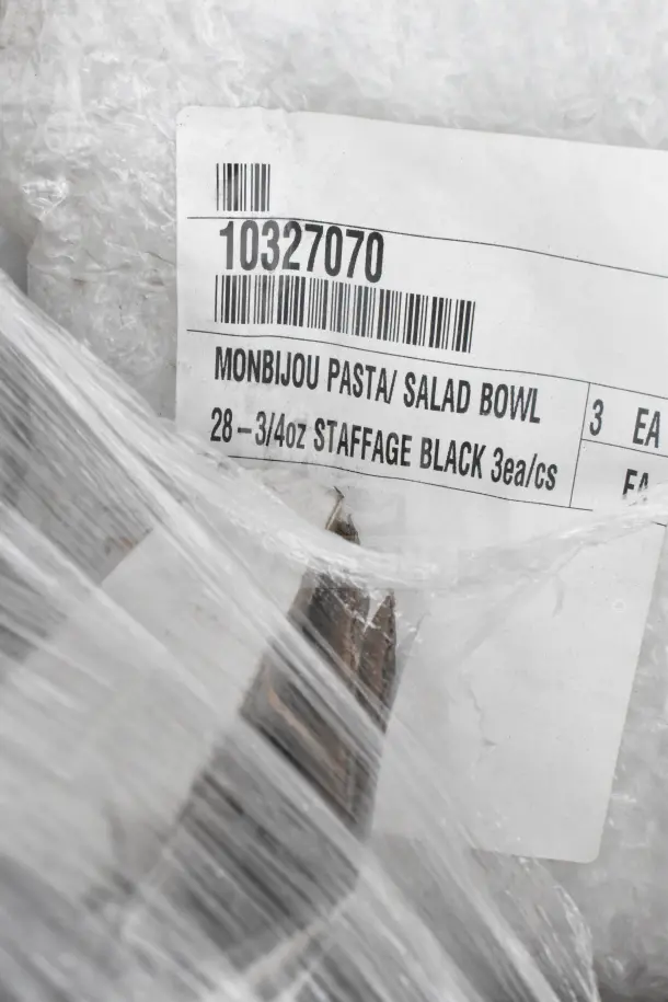 Monbijou pasta/salad bowls labeled "3 EA, 28-3/4oz Staffage Black" seen through protective wrapping, barcode visible.