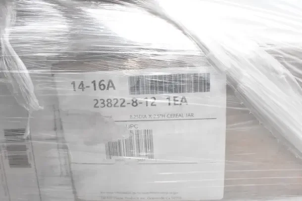 Pallet wrapped in plastic showing label with "23822-8-12 1EA" and "8.25 DIA x 2.5"H Cereal Jar" details.